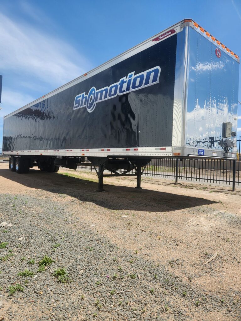 A black trailer parked on the side of a road.