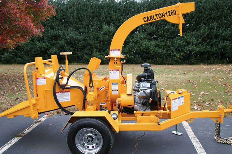 A yellow log splitter sitting on top of a road.